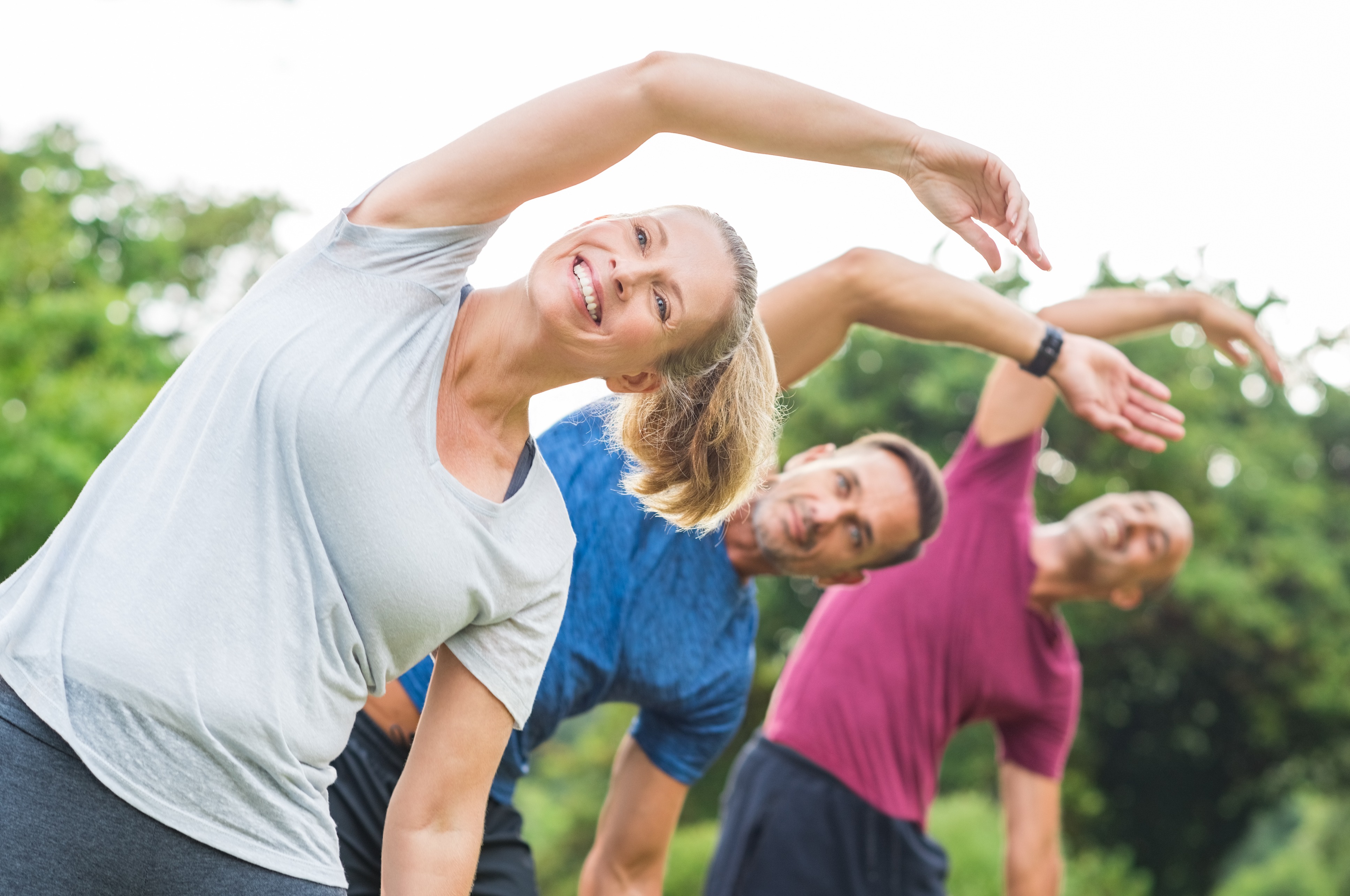 Diverse group of adults stretching together during an outdoor exercise class