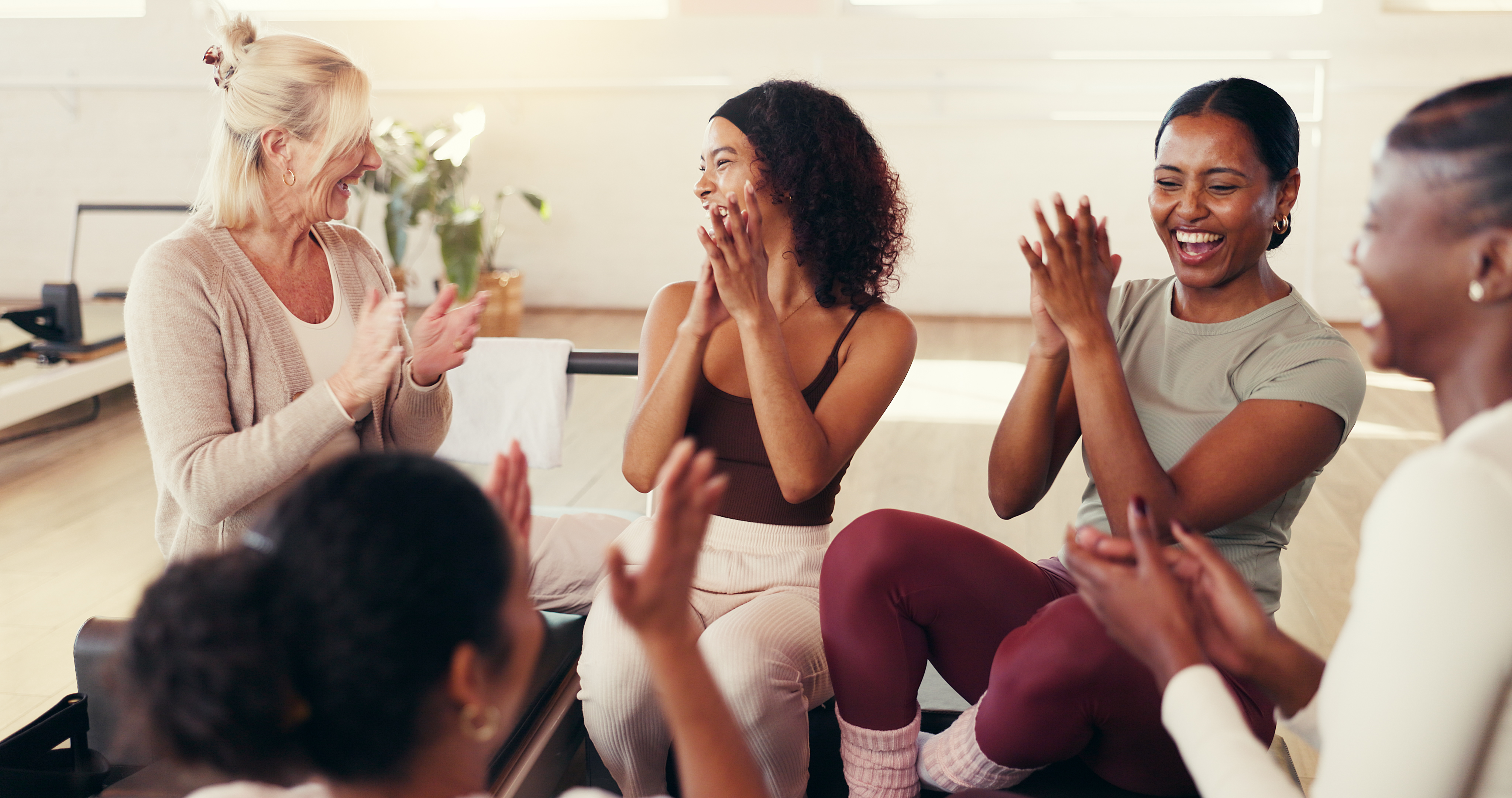 A diverse group of women laughing and celebrating together in a bright wellness studio